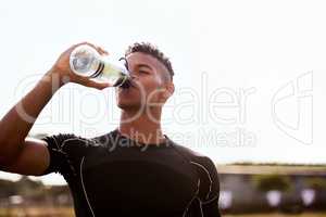 Get hydrated, were going in for the second half. Shot of a young man drinking water after playing a game of rugby.