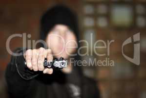 Criminal in control. View of a man holding a gun and pointing at you.