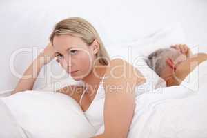 Relationship breakdown. Beautiful woman looking unhappy with her back to her husband in bed.
