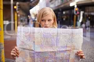 I think Im lost.... Shot of a young woman holding a map while touring abroad.