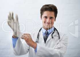 This wont take long..... Shot of a smiling doctor pulling on a surgical glove.