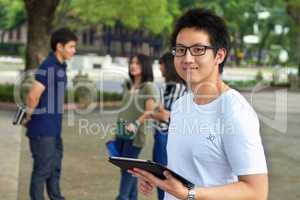 Using modern technology to studying for his finals. Portrait of a handsome young student working on his digital tablet outside.