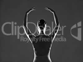She lives to dance. Silhouette of a young ballerina dancing against a dark background.