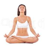 In total harmony. A fit young woman doing yoga while against a white background (lotus position).