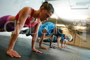 Working the upper body. Shot of a group of people working out in the gym.