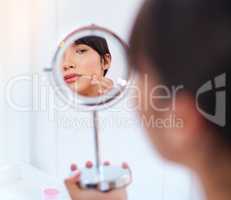 Where did you come from. Shot of a stressed out attractive young woman noticing a zit on her face while looking at her refection in a mirror at home during the day.