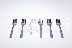 Sometimes being different has no benefits. A broken fork lying in a row of forks.