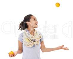 Shes got her eye on balancing a healthy diet. Young woman smiling while juggling some fresh oranges.