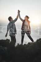 This couple conquered the mountain. Shot of a young couple high fiving after making it to the top of the mountain.