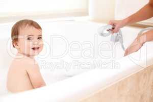 Bath time = fun. Portrait of an adorable baby girl in the bath while her mother watches over her.