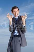 Oh yeah. A young businessman signing a-okay against a blue sky.