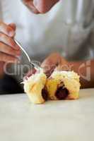 Its the intricate details that make you a chef. Close up of a baker putting frosting on a cupcake that is cut in half to show the chocolatey centre.