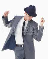 With a snap and shuffle. A young man in a suit and hat dancing against a white background.