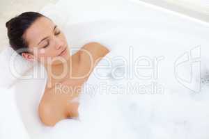 Indulging in a bubble bath. Shot of a beautiful young woman relaxing in the bathtub.