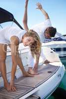 Doing their morning exercises. Young couple exercising together on a yacht.