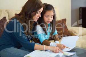 Encouraging a love of learning. Little girl getting help with her homework from her mother.