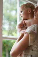 Whats out there. A baby boy and his mother looking out the window.