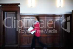 In a hurry with important documents. Side view of a female legal person walking quickly with some documents.