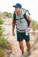 Its important to keep hydrated. Happy young hiker walking with a bottle of water in his hand.