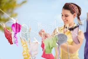 Its laundry day. Attractive young woman hanging up her washing on a line outside.