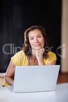 Thinking something to add to her calendar. A young woman working on her laptop at home.