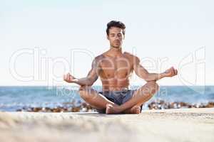 Seeking enlightenment in nature. A young man meditating next to the ocean.