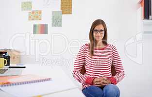 She finds a tidy environment more conducive for her creativity. Portrait of a young woman sitting at a desk.