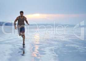 Finding inspiration through fitness. A handsome young man exercising on the beach in the early morning.