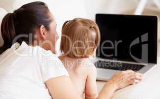 Getting an early start at learning. A mother and her little daughter looking at a laptop together.