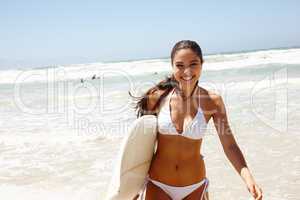 Home is where the waves are. Portrait of a female surfer holding her surfboard at the beach.