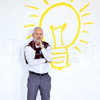 Hes an ideas man. Portrait of a mature businessman standing against a white background with a lightbulb on it.