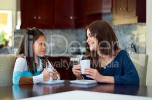 Bonding over some hot chocolate. Sweet little girl sharing a hot chocolate with her mother at home.