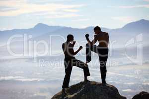 Extreme kickboxing. A male kickboxer practising their technique on a mountain peak.