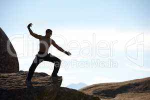Kickboxing on the mountain. A male athlete kickboxing on the edge of a cliff on a mountain.