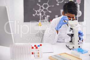 Another day in the lab. A young scientist using a microscope at her desk in her lab.
