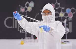 Caution in the lab. A young scientist in protective clothing using a pipet in her lab.
