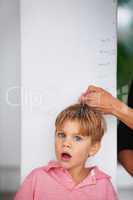 Wow, youve really grown. Portrait of a shocked young boy having his height measured by his mother on the kitchen wall.