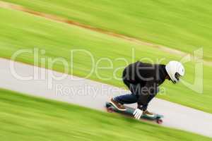 He lives life in the fast lane. Shot of a man skateboarding down a lane at high speed on his board.