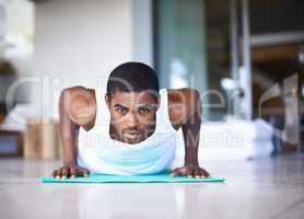 This is what commitment looks like. Shot of a young man doing push ups on an exercise mat.