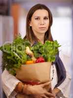 She knows the value of healthy food choices. Attractive woman holding a paper bag of fresh produce.