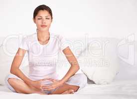 Finding her spiritual center. A young woman sitting crossed legged and meditating.