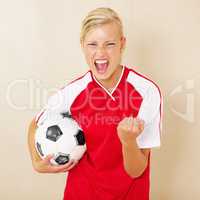 Champions of the league. Shot of a young woman dressed in a soccer uniform celebrating and holding a soccer ball.