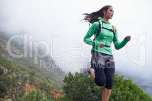 She progresses in her fitness everyday. A young woman sprinting along a mountain road on a crisp morning.