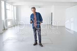 Ire got plans for this space. A portrait of a mature man standing in an empty room holding building plans.