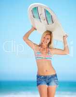 Summer vacation is finally here. A surfer girl at the beach holding up her surfboard getting ready to surf.