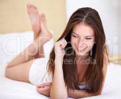 What time is it there. A gorgeous young woman talking on the phone while lying on her bed.