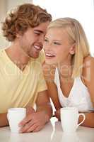 His jokes amuse her. Portrait of a couple sitting together and enjoying a cup of coffee.