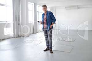 Envisioning great things for this space. A portrait of a mature man standing in an empty room holding building plans.
