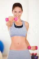 Shaping up. Portrait of a beautiful young woman training with a dumbbell in the gym.