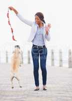 Jump higher. A beautiful african woman playing with her dog on the promenade.